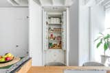 Bespoke storage lines the left wall of the kitchen. The hand-turned white-oak knobs complements the cabinetry and centralized island.