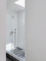 A skylight ushers ample natural light into the glass shower, complete with Fireclay tile.