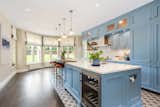 The baby-blue cabinets contrast with a white subway-tiled backsplash and mosaic-tiled flooring. A large bay window overlooks the front driveway and lawn, while allowing tons of natural light into the space.