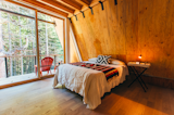 Exposed wood finishes continue into the bedrooms. Large, sliding doors frame picturesque views of the forest waiting outside.