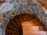 Steps away from the kitchen is a striking spiral staircase with wooden treads that follow along the curved stone wall.