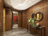 The home's private elevator opens to a Walnut-panned foyer, which also features a custom Lolli e Memmoli Crystal Alpha Chandelier and Crigio Carnico slab marble flooring. The furnishings are by Bottega Veneta and Mauro Mori.