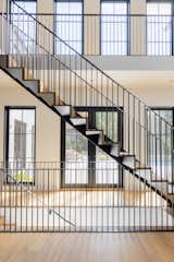 The central staircase and landing is a dramatic focal point, enhanced by the home’s minimal aesthetic and a two-story backdrop of windows. "Having the double-height volume allowed us to focus everyone to the outdoors," comments Winberry.&nbsp;