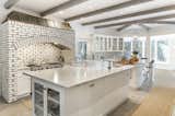The large kitchen features exposed beams and a brick alcove that was originally a fireplace. Other finishes include Carerra marble contrasting with shades fixtures of bronze and copper.&nbsp;