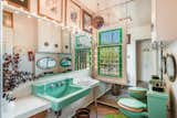 This half bath offers original fixtures and finishes—including stained glass windows and a mint-green sink and toilet.