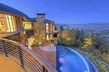 The home blends into the hillside with its natural stone and glass facade. Numerous windows, decks, and patios provide panoramic views of Park City and Wasatch Mountain.
