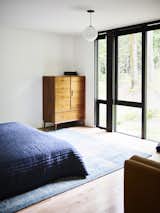 Bedroom, Bed, Rug, Dresser, Pendant, and Light Hardwood A peek into one of the bedrooms.  Bedroom Dresser Rug Bed Pendant Photos from This Cor-Ten Steel Cabin Is a Woodland Escape for the Generations