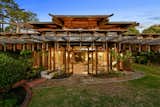 From the lower level, the structure resembles a Japanese pagoda, complete with a water feature that flows inside and out. French doors provide access to extensive terracing, patios, and gardens nestled into the lush landscape.