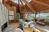An original raised platform underneath the central skylight provides a more intimate area near a new slab-stone fireplace. Floor-to-ceiling, multi-paneled windows and doors look out onto a deck and views of the Golden Gate Bridge.  Photo 8 of 14 in A Berkeley Home Designed by Two Frank Lloyd Wright Protégés Seeks $2.65M