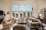 Arched windows and French doors span a south-facing wall in the family room. The large space looks out onto a patio and the pool below.