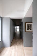 Light wood flooring is paired with gray masonry and white walls in the bright interiors.