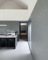 The monochromatic kitchen features a dark gray island and windows positioned for views of the landscape.&nbsp;