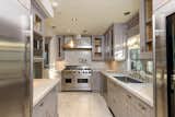 In the kitchen, high-end appliances and custom cabinetry line the walls, while marble caps the counters and floors.