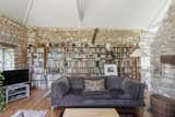 Living Room, Sofa, Light Hardwood Floor, Floor Lighting, Lamps, and Bookcase A central feature of the space are the stacked stone walls, which line all three sides of the room and feature original inscriptions from local workers.  Photo 7 of 13 in This Darling Converted Barn in an English Village Seeks £980K