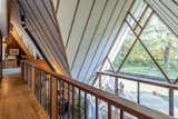 The view from a loft above the dining room, which provides a different perspective of the interlocking gable design. Bands of geometric forms are created by a series of&nbsp;frames dividing the glasswork, as well as strips of redwood lining the ceilings.