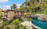 Built into the hillside opposite the home is a lagoon-like swimming pool with cascading waterfalls and lush greenery.The 7,000-square-foot lot flourishes with extensive landscaping.