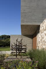 A weathered metal sculpture at the front door echoes the larger piece in the home’s central yard.