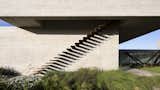 A floating staircase made of Cor-Ten steel provides access to the upper story from the central yard.