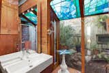A wood-clad bathroom on the lower level features another solarium-like corner, topped with stained glass and surrounded by a private rock garden.