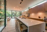 The kitchen wraps around the atrium-like courtyard. Clerestory windows and a continuous row of cabinetry provides strong horizontal elements to connect the kitchen and dining room.  Photo 5 of 11 in This Slick Austin Home Offered at $1.95M Stretches Like an Accordion