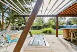 A large pergola imitates the structure's post-and-beam design. The patio flows out onto a grassy lawn and other shady sections of the 10,000-square-foot lot.