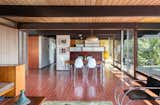 Steel beams form a continuous skeleton across the width of the home, extending out to form an overhang and covering a deck off of the kitchen. The great room is an open space running from the main entrance to the kitchen.