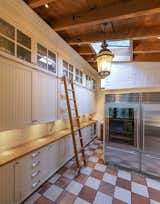 A wall of cabinets in the corner provides additional pantry or storage space, along with a professional-grade refrigerator and freezer unit. A skylight brightens the otherwise dark corner.