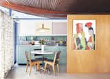A 1950s home in California undergoes a renovation that retains the essence of the vintage home. The kitchen was relocated to its designated place and reinstalled as per the building specs of the original architect, Walter S. White. A stainless-steel counter and sink, powder-coated cabinets, and sliding panels in pastels replicate the original 1955 version while contemporary updates include Vola faucets, Heath Ceramics tiles, sliding freezer drawers, an induction range, and a refrigerator by Jennair.