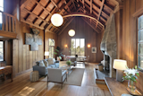Featuring floor-to-ceiling redwood paneling and arched beams, the living room offers a dramatic room in which to gather. An original interior balcony overlooks the space from the second floor.