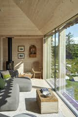 Floor-to-ceiling windows look out onto the woods and meadow surrounding the home. The stove is by Hwam.