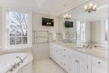 The master bathroom is dressed in marble and features a large soaking tub in the corner.