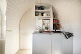 A compact kitchen is custom-built for each space. A curved doorway leads to the bathroom.