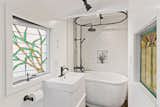 The remodeled bath features a small soaking tub and custom-designed, stained glass windows.