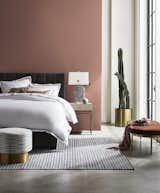 The Butler Channel bed in Boulevard Graphite velvet sits alongside a Solange faux-shagreen side table in cream, a Colburn cocktail ottoman in Vivid Terracotta velvet, and a Margaux swivel ottoman in Taos Silver.