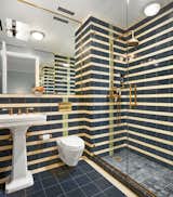 A look at the second full bathroom, which makes use of a dichromatic striped tile pattern to wrap the walls and shower. The home also features a marble-clad half-bath, complete with vintage Judscott wallpaper.
