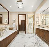 The luxurious, marble-clad master bathroom features an oversized Zuma soaking tub along one wall and a double vanity along the other. A large shower sits at the end.