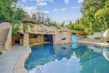 A large pool with swim-up bar and grotto awaits in the backyard.&nbsp;The original pool reportedly featured an underground tunnel and secret, bombproof room, although the agent is unsure if that feature survived the renovations.