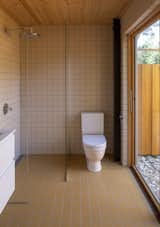 The cabin's single bathroom is located adjacent to the master bedroom and is covered in ocher-colored tile. A fenced-in outdoor bathing area is accessible via a sliding glass door.