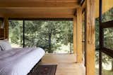 Bedroom, Bed, Medium Hardwood Floor, and Track Lighting The glass walls in the master bedroom allow the treetops to act as a natural curtain, and create the feeling of sleeping in a tree house.  Photos from A Cantilevered Home in Southern Chile Takes Design Cues From Lake, Trees, and Sky