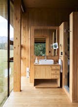 Bath Room, Wood Counter, Medium Hardwood Floor, Vessel Sink, and Enclosed Shower The raw pine that wraps around the vanity, walls, flooring and ceiling in the bath lends texture and warmth.  Photos from A Cantilevered Home in Southern Chile Takes Design Cues From Lake, Trees, and Sky