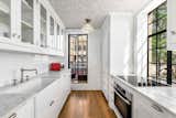 The bright and airy chef's kitchen features marble countertops, along with stainless-steel Miele and Sub-Zero appliances. The walls are clad in white subway tiles, complementing the cabinetry and contrasting with the refinished hardwood floors.