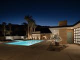 At night, recessed lights trace the structure along the overhang while the pool glows in the moonlight.