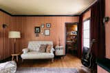 Black molding and velvet drapery enhance the library/study space, which includes a writer's nook in the corner. The space also includes a brick fireplace along the opposite wall.