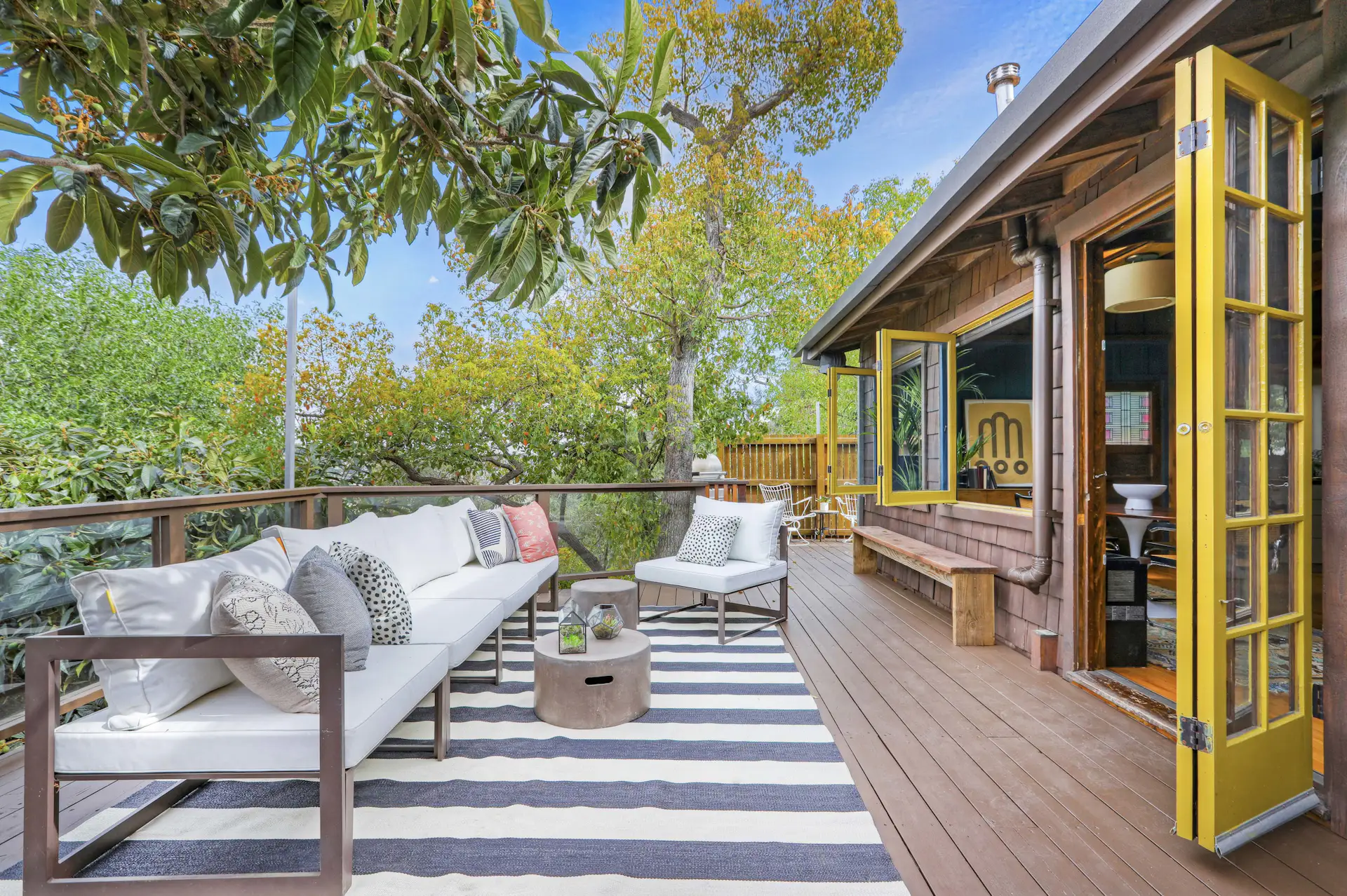 The large deck is surrounded by a lush canopy of trees.