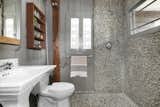 Two windows invite natural light into the pebble-stone bathroom.