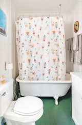 Green-painted hardwoods add a playful pop of color in the bathroom, which also offers a clawfoot bathtub.
