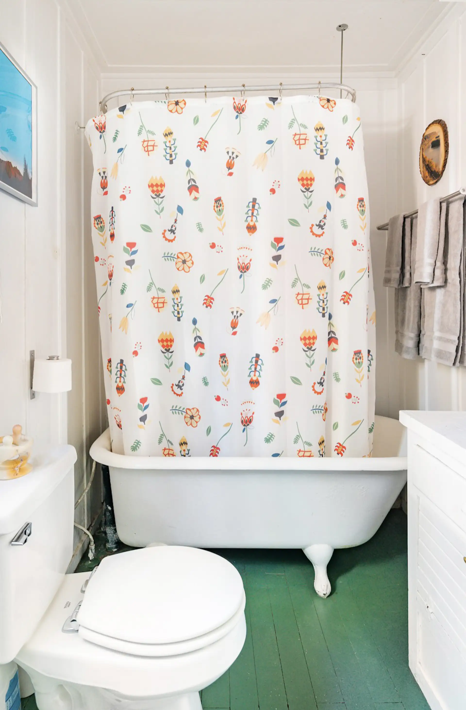 Green-painted hardwoods add a playful pop of color in the bathroom, which also offers a clawfoot bathtub.