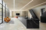 Strips of recessed lighting run along the ceiling and down the walls. The kitchen is made of a monumental island stretching along the center of the space.