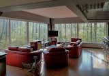 Inside, the upper-level is now an open living area. The windows provide a panoramic view of the forested area.