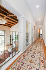 A long hallway overlooks the living space as it leads to the master bedroom.